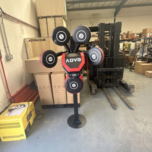 ADVG Adjustable Boxmaster/Sparmaster front view beside stock boxes and a forklift