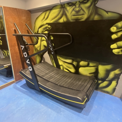 ADVG Commercial Curved Treadmill CurveMax 1.0 in a gym in front of a painted mural