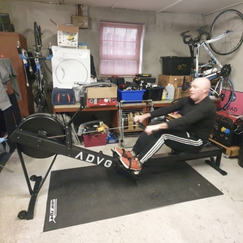 ADVG RowErg PowerMax 1.0 rowing machine in use in a home garage gym